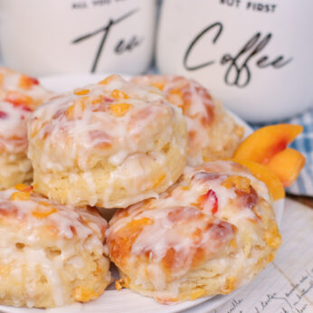 fluffy, peach buttermilk biscuits piled high on a plate