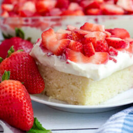 Strawberry shortcake cake topped with whipped cream cheese frosting and fresh strawberries