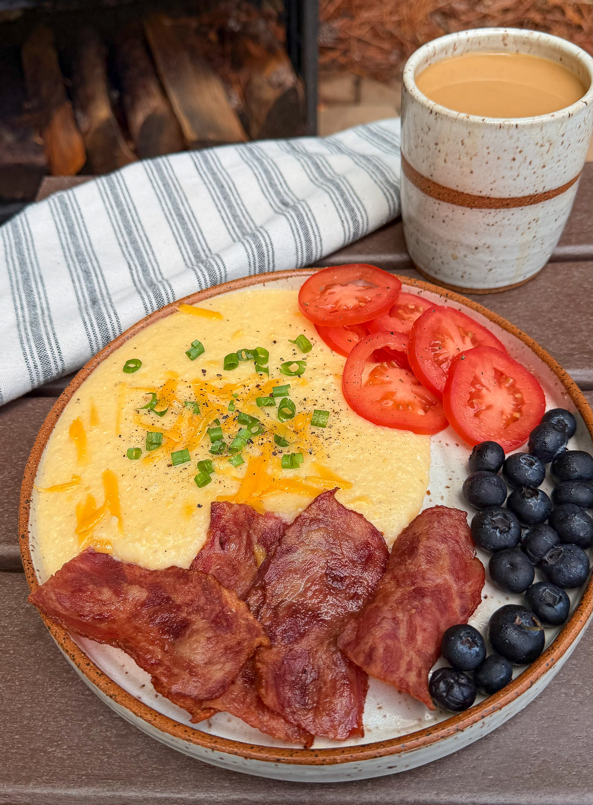 Easy breakfast idea with a plate of cheese grits, tomatoes, blueberries and bacon.