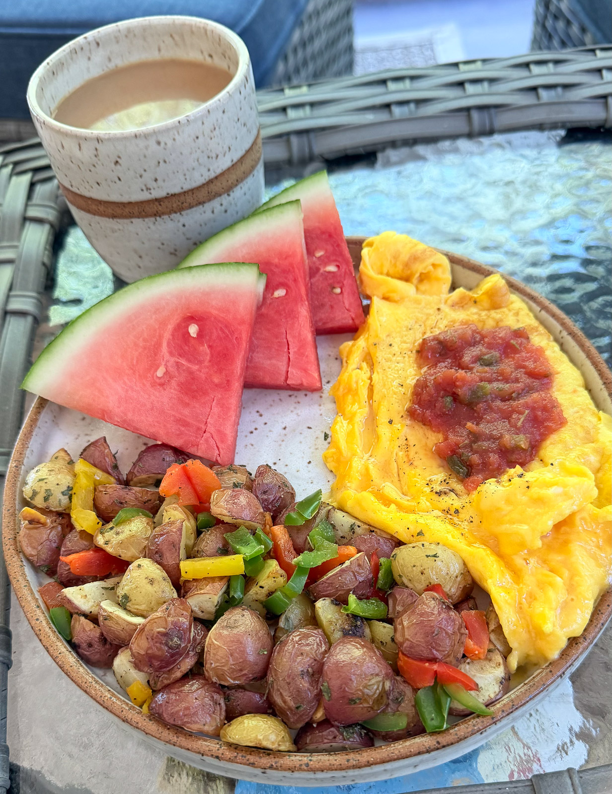 Breakfast plate with cheese omelet, sliced watermelon, and roasted breakfast potatoes.